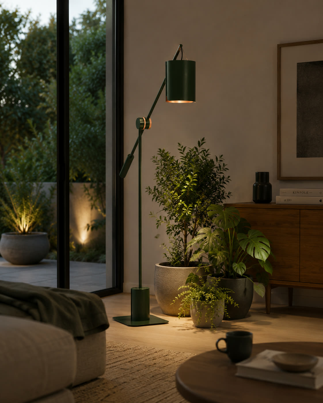 A living room at dusk lit by Anthos, ferns and a monstera under the beam